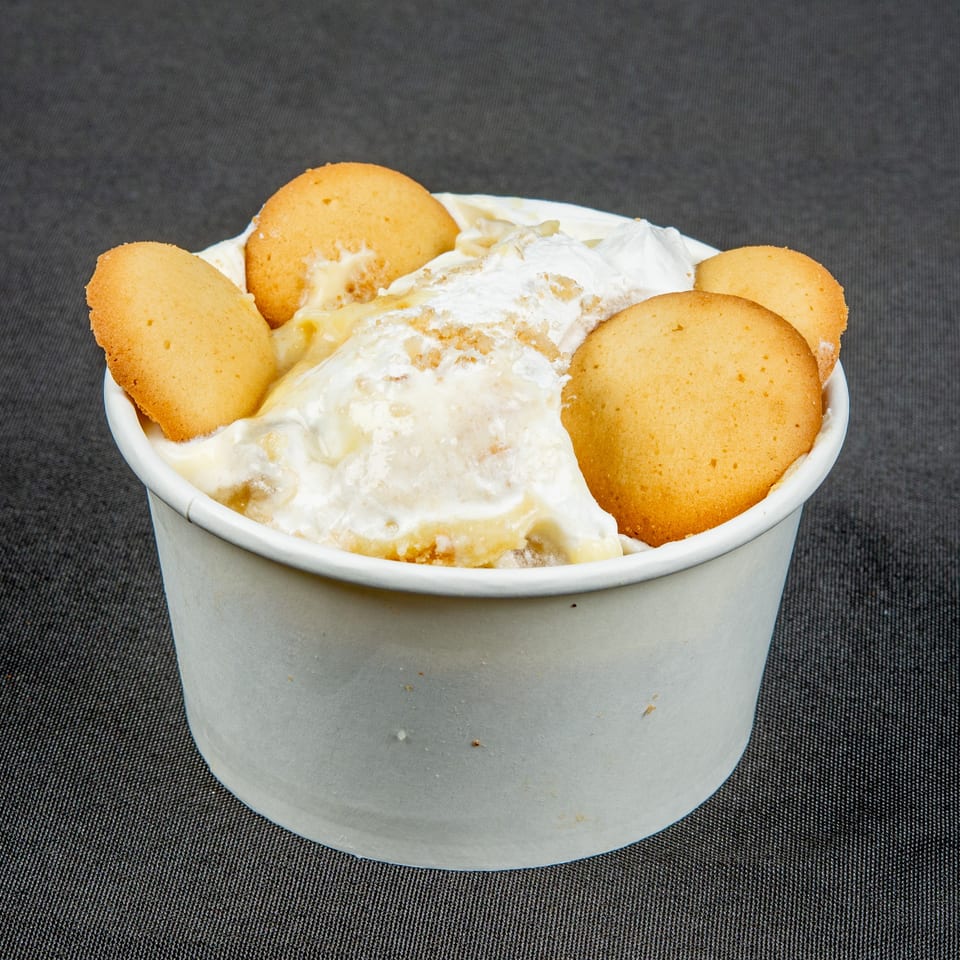 Cup of creamy banana pudding topped with whipped cream and golden vanilla wafer cookies.