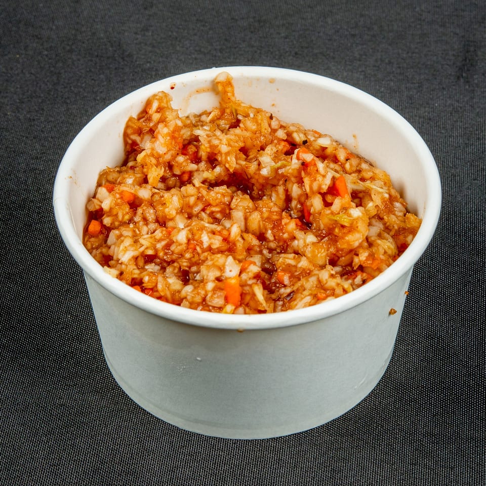 A white bowl holds saucy fried rice with diced carrots and vegetables on a dark textured surface.