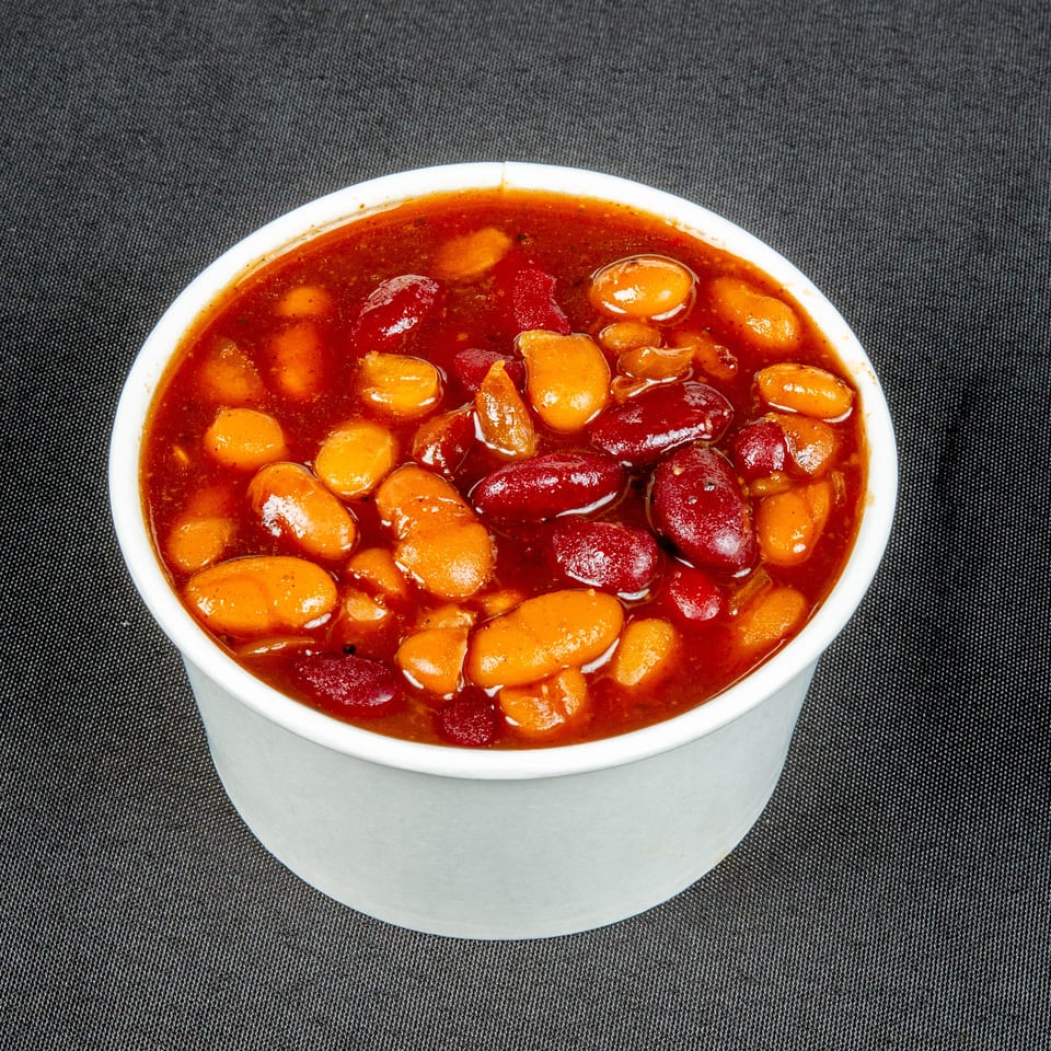 Bowl of kidney and pinto beans simmered in a glossy red sauce on a dark textured surface.